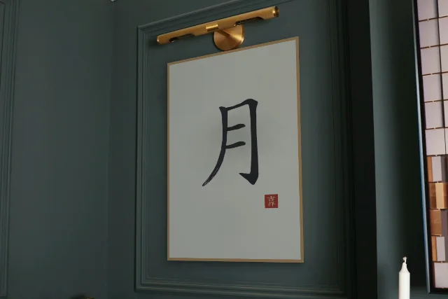 Lune à l'encre, riz gris : affiche encadrée chêne sous une lampe de tableau, mur vert profond