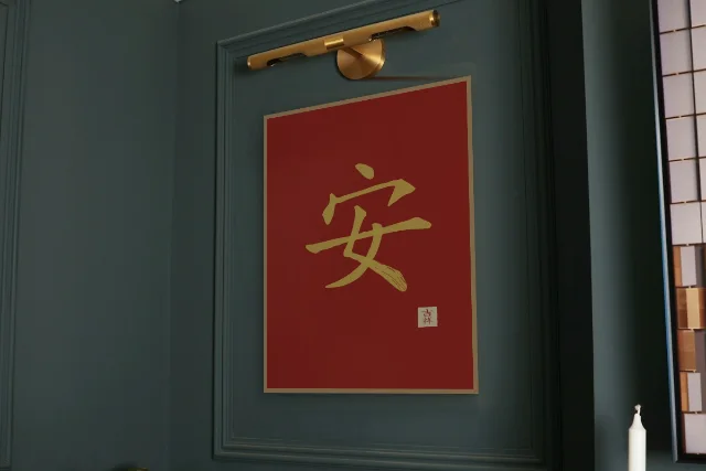 Paix à l'encre, laque rouge : affiche encadrée chêne sous une lampe de tableau, mur vert profond