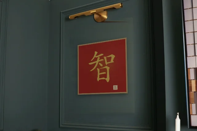 Sagesse à l'encre, laque rouge : affiche encadrée chêne sous une lampe de tableau, mur vert profond