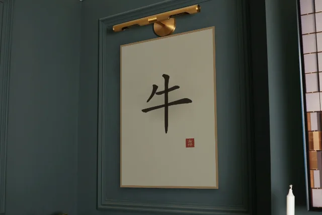 Signe du Buffle à l'encre, sable ocre : affiche encadrée chêne sous une lampe de tableau, mur vert profond