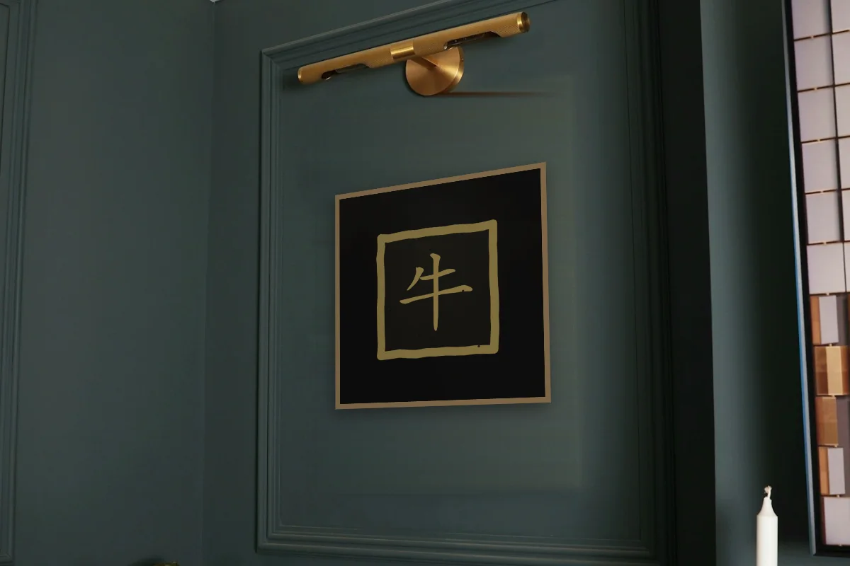Signe du Buffle en sceau, encre d’or. Photo d'illustration : Affiche encadrée chêne sous une lampe de tableau, mur vert profond, œuvre en 50 × 50 cm, à l'échelle. Photo de la pièce : Paul Yarnell (Unsplash).