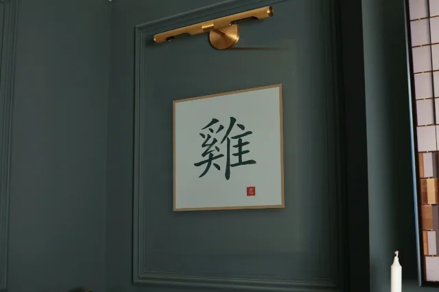 Signe du Coq à l'encre, jade : affiche encadrée chêne sous une lampe de tableau, mur vert profond